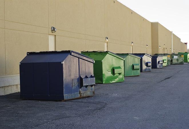 a construction worker disposing of debris into a dumpster in Alda